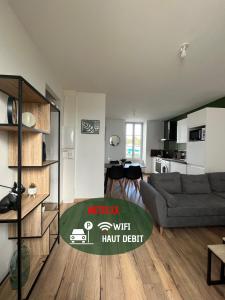 sala de estar con sofá gris y cocina en Le Duplex Tout Confort, en Bressuire