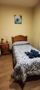 a bedroom with a bed with a blue and white comforter at Hostal Hotel EL Chato in El Barraco