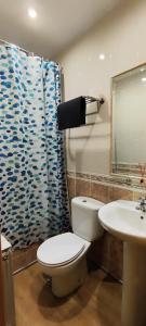 y baño con aseo, lavamanos y cortina de ducha. en Hostal Hotel EL Chato en El Barraco