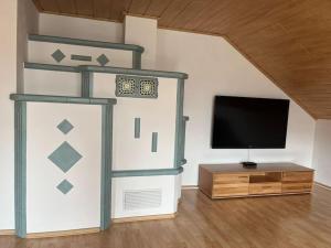 ein Wohnzimmer mit einem Flachbild-TV und einem TV-Stand in der Unterkunft Ferienwohnung Aischgrund in Hallerndorf