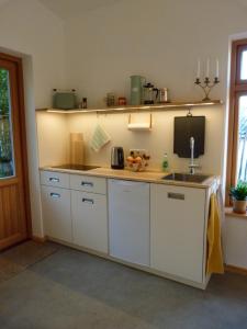 uma cozinha com armários brancos, um lavatório e um balcão em Grüne Oase em Kiel