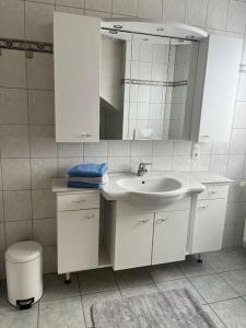 ein weißes Badezimmer mit einem Waschbecken und einem Spiegel in der Unterkunft Ferienwohnung Aischgrund in Hallerndorf