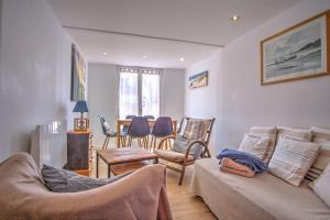 een woonkamer met een bank en stoelen bij Chalet au calme au milieu de la forêt. in Gujan-Mestras