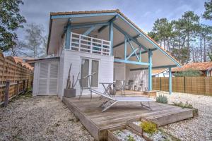 a tiny house with a porch and a deck at Chalet au calme au milieu de la forêt. in Gujan-Mestras