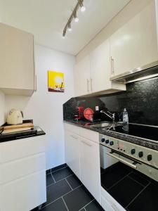 a kitchen with white cabinets and a stove top oven at Chalet-Studio in Leukerbad