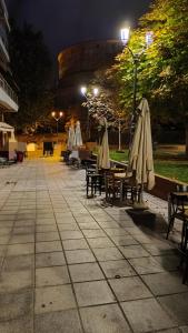 um grupo de mesas e guarda-sóis numa calçada à noite em M&M's house em Tessalônica