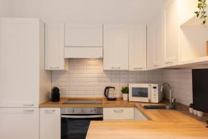 Biała kuchnia z białymi szafkami i kuchenką mikrofalową w obiekcie Mezzofanti - TRE PONTI w Mediolanie