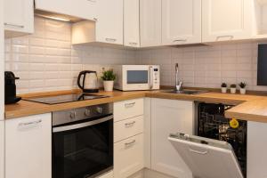 kuchnia z białymi szafkami, zlewem i kuchenką mikrofalową w obiekcie Mezzofanti - TRE PONTI w Mediolanie