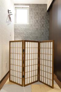 ajar doors in a room with a brick wall at Hostel LodgingTokyo Minowa in Tokyo