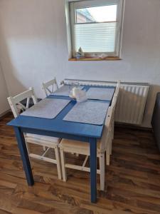 un tavolo blu e sedie in una stanza con finestra di Wohnung Nordseebriese a Norden