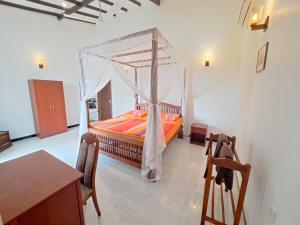 1 dormitorio con cama con dosel, mesa y sillas en Villa 76, en Weligama