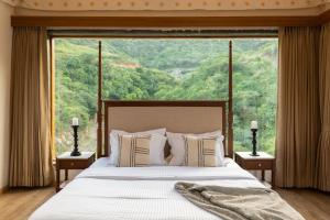 a bedroom with a bed with a large window at SaffronStays Moringa Valley - Oak Villa in Udaipur