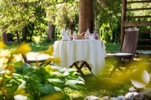 una mesa con un mantel blanco y sillas en un jardín en Art Hotel Kristal en Bohinj