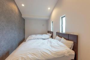 a bedroom with a bed with white sheets and pillows at asoha in Minami Aso