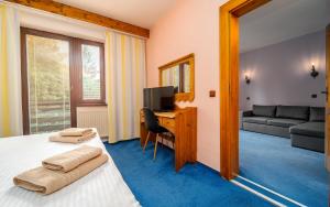 a bedroom with a bed and a desk with a television at Hotel Ondras z Beskyd in Ostravice