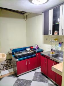 a kitchen with red cabinets and a stove at Bito Homestay 