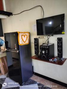 a room with a tv and a refrigerator with speakers at Bito Homestay 