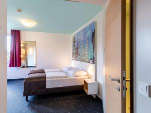 a bedroom with a bed with a painting on the wall at B&B Hotel Nürnberg-City in Nuremberg