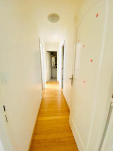 un corridoio di un appartamento con pareti bianche e pavimenti in legno di Lovely appart near Stade de France ad Aubervilliers