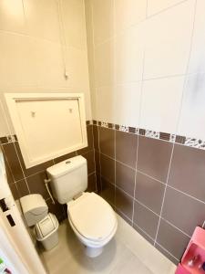 uma casa de banho com um WC branco e azulejos cinzentos em Lovely appart near Stade de France em Aubervilliers