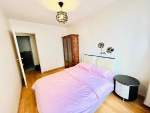 ein Schlafzimmer mit einem rosa Bett und einem Kronleuchter in der Unterkunft Lovely appart near Stade de France in Aubervilliers