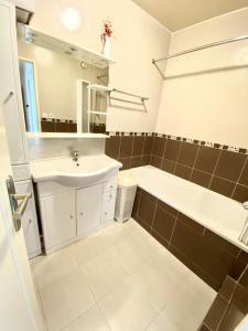 ein Badezimmer mit einem Waschbecken, einer Badewanne und einem Spiegel in der Unterkunft Lovely appart near Stade de France in Aubervilliers