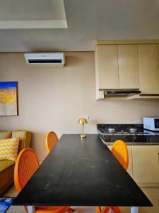 une cuisine avec une table noire et des chaises orange dans l'établissement Ciputra International Superblock Puri Kembangan, à Jakarta