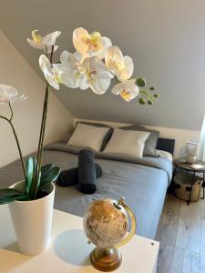 Zimmer mit einem Bett und einem Tisch mit einer Blume in der Unterkunft L'Hellébore - Centre ville de Rennes in Rennes