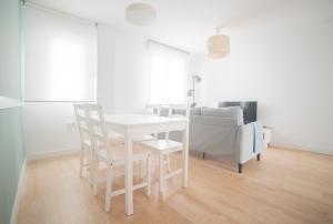 un comedor blanco con una mesa y sillas blancas en Apartamento Balbín IV, en Gijón