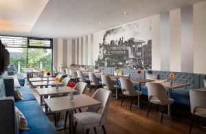 een restaurant met tafels en stoelen en een treinmuurschildering bij Leonardo Hotel Vienna Hauptbahnhof in Wenen