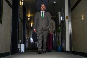 Um homem de fato e gravata verde a andar pelo corredor. em AG Hotel em Abu Dhabi