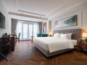 ein Hotelzimmer mit einem großen weißen Bett und einem Schreibtisch in der Unterkunft L'Signature Hotel & Spa in Hanoi