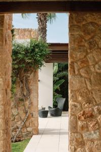 um pátio aberto com uma parede de pedra e uma árvore em Villa Sophie - Luxury Style & Sunset View em Sant Josep de sa Talaia