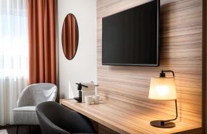 um quarto de hotel com uma televisão na parede em Leonardo Hotel Vienna Hauptbahnhof em Viena