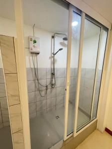 La salle de bains est pourvue d'une douche et d'une porte en verre. dans l'établissement The Sports Lounge, à Pattaya