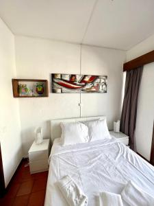 een slaapkamer met een wit bed en 2 schilderijen aan de muur bij Nice & Cozy Little Studio with Terrace in Estoril in Estoril