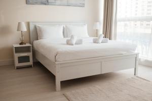 a white bedroom with a white bed with white pillows at Classy 1BR in Al Sahab Dubai Marina in Dubai