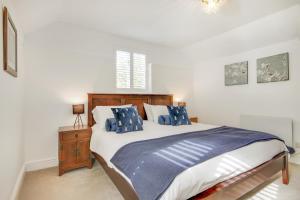 1 dormitorio con 1 cama grande con almohadas azules en Pass the Keys Lovely Countryside Coach Cottage en Tonbridge