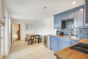 a kitchen with blue cabinets and a table at Pass the Keys Lovely Countryside Coach Cottage in Tonbridge