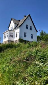 Biały dom na szczycie trawiastego wzgórza w obiekcie Villa Henrikke Myhre w mieście Osøyro