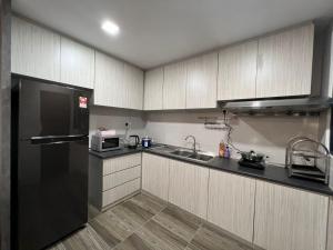 een keuken met een zwarte koelkast en een wastafel bij A.Foo Homestay 4.3 @ Vivacity Megamall Jazz Suite 4 in Kuching