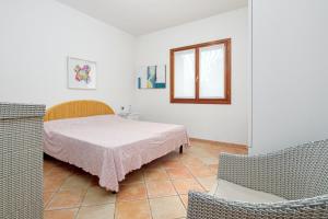 een slaapkamer met een bed, een raam en 2 stoelen bij Villa Cedrino in San Teodoro