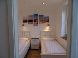 twee bedden in een kleine kamer met witte muren bij Ferienhaus-Kegelrobbe in Dornumersiel