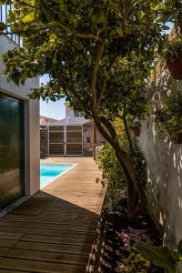a wooden walkway with a tree next to a pool at Sea´ya Thoughtful Stays - Villa Areia in Cascais
