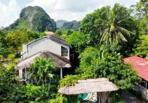 a house in the jungle with mountains in the background at Nan House - Tam Coc in Ninh Binh