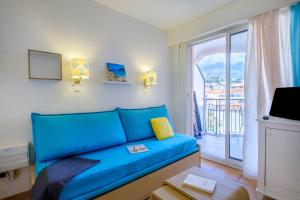 - un canapé bleu dans le salon avec balcon dans l'établissement Résidence Pierre & Vacances Les Rivages Du Parc, à Menton