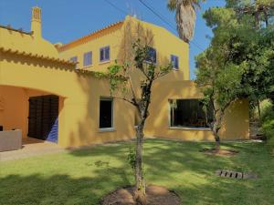 ein gelbes Haus mit einem Baum davor in der Unterkunft Fashion Villa in Vilamoura with Private Pool in Quarteira