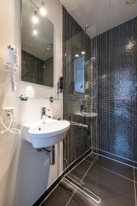 a white bathroom with a sink and a shower at Acostar Hotel in Amsterdam