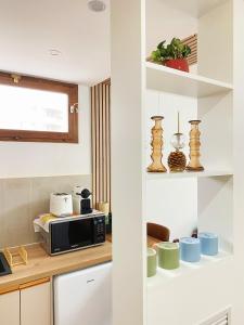eine Küche mit weißen Schränken und einer Mikrowelle in der Unterkunft Chez les deux garçons in Montrouge
