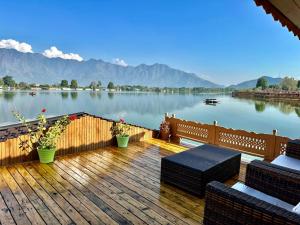 a wooden deck with chairs and a view of a lake at New Jacquline Heritage Houseboats in Srinagar